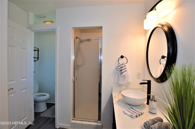 bathroom featuring hardwood / wood-style floors, sink, a shower with shower door, and toilet