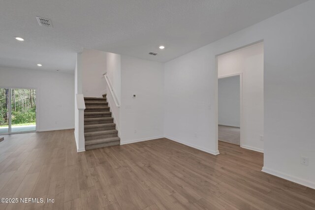 empty room with light hardwood / wood-style floors and a textured ceiling