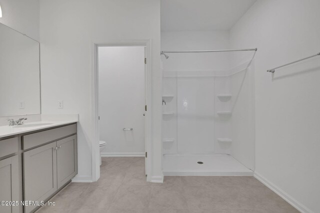 bathroom featuring vanity, tile patterned flooring, a shower, and toilet