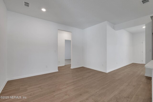 unfurnished room with a textured ceiling and light wood-type flooring