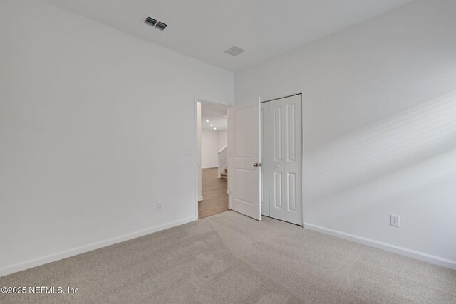 unfurnished bedroom with light colored carpet and a closet