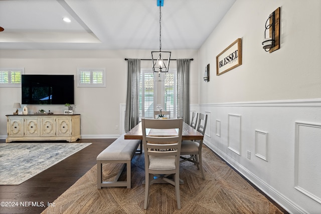 dining room with a raised ceiling, dark hardwood / wood-style flooring, and an inviting chandelier