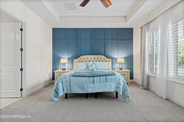 carpeted bedroom featuring ceiling fan and a raised ceiling