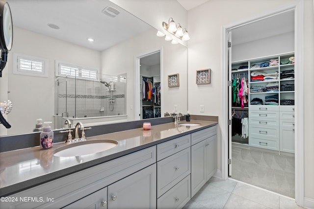 bathroom with tile patterned flooring, a tile shower, and dual bowl vanity