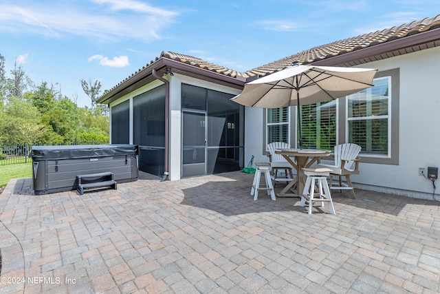 view of patio featuring a hot tub and a sunroom