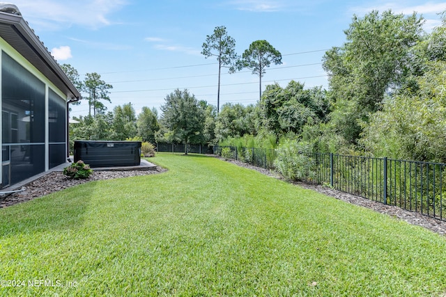 view of yard featuring a sunroom and a hot tub