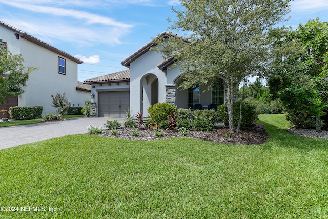 mediterranean / spanish-style home featuring a garage and a front lawn