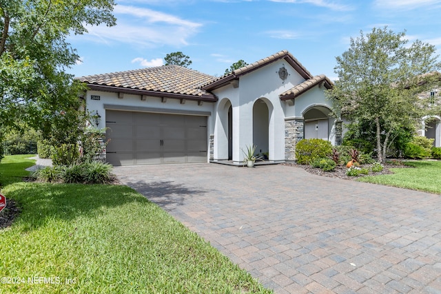 mediterranean / spanish house with a garage and a front yard