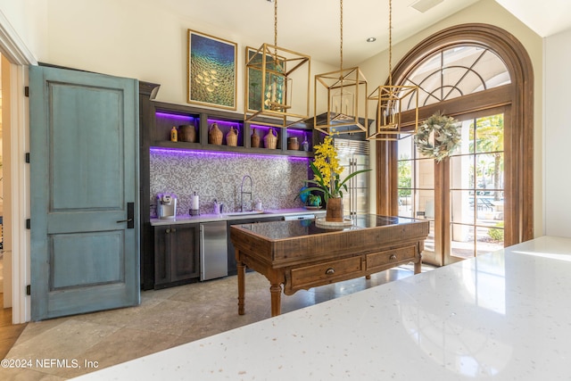 kitchen featuring tasteful backsplash, light tile patterned floors, dishwasher, pendant lighting, and sink