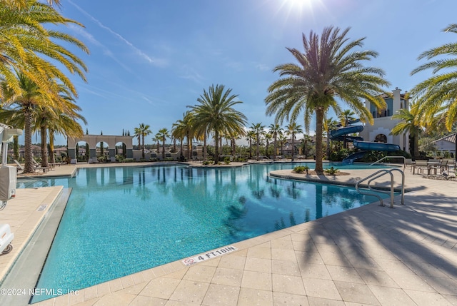 view of pool with a water slide and a patio area