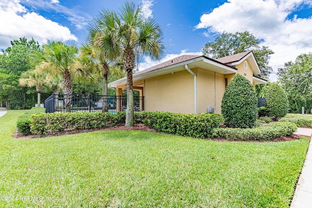 view of side of home featuring a lawn, fence, and stucco siding