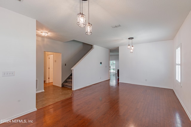 unfurnished living room featuring hardwood / wood-style flooring and a chandelier