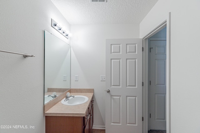 bathroom featuring a textured ceiling, visible vents, and vanity