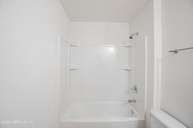 bathroom with tub / shower combination, a textured ceiling, and toilet