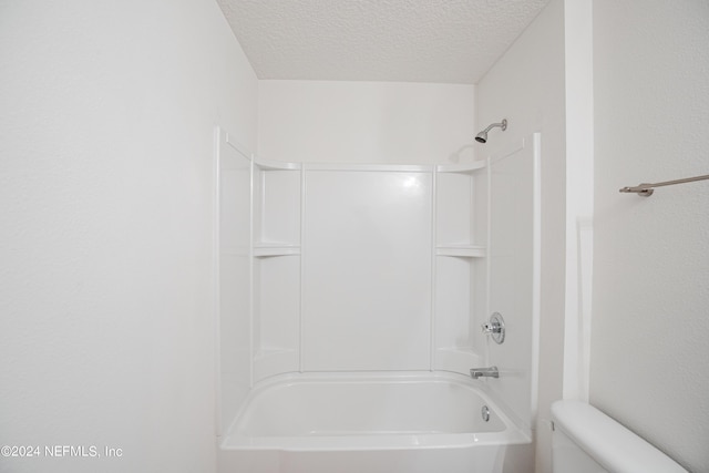 bathroom featuring  shower combination, a textured ceiling, and toilet