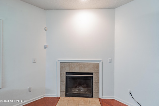 room details with a textured ceiling, baseboards, a tiled fireplace, and wood finished floors