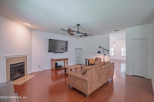 living area with a textured ceiling, a fireplace, visible vents, and wood finished floors