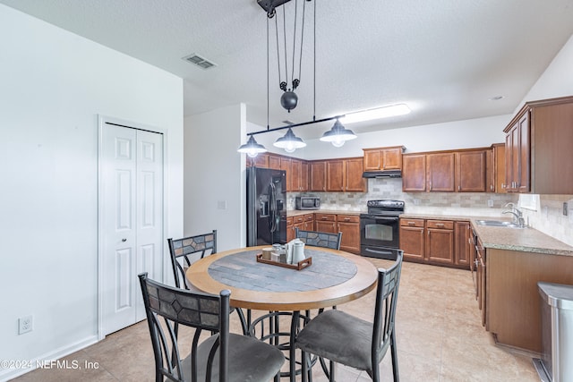 kitchen featuring decorative backsplash, pendant lighting, light tile patterned floors, black appliances, and sink