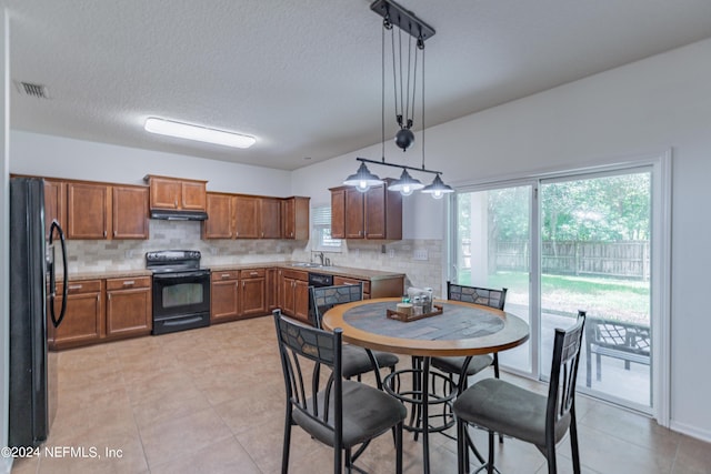 kitchen with decorative backsplash, brown cabinets, under cabinet range hood, black appliances, and a sink