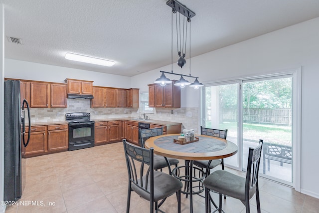 kitchen featuring decorative backsplash, light tile patterned floors, hanging light fixtures, and black appliances