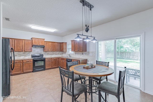 kitchen with brown cabinets, backsplash, under cabinet range hood, black appliances, and a sink