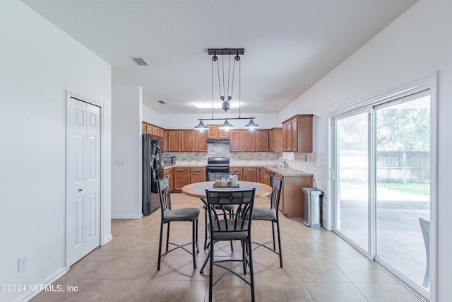 kitchen with black refrigerator, hanging light fixtures, backsplash, sink, and range with electric cooktop