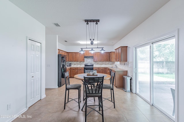 kitchen with a sink, visible vents, black fridge, decorative backsplash, and electric range oven