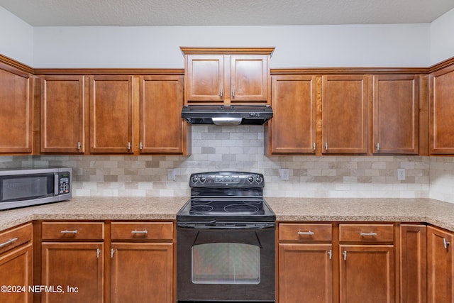 kitchen with under cabinet range hood, black range with electric stovetop, light countertops, decorative backsplash, and stainless steel microwave