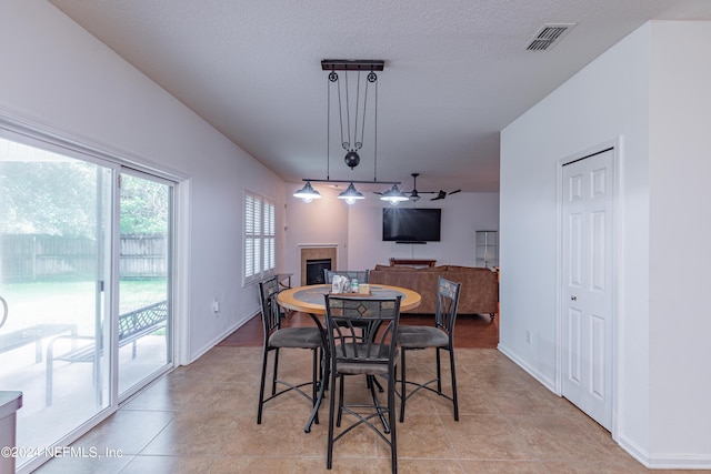 dining space with a glass covered fireplace, baseboards, visible vents, and rail lighting