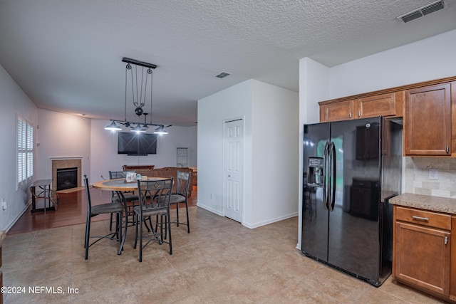 dining area featuring a tile fireplace, visible vents, a textured ceiling, and baseboards