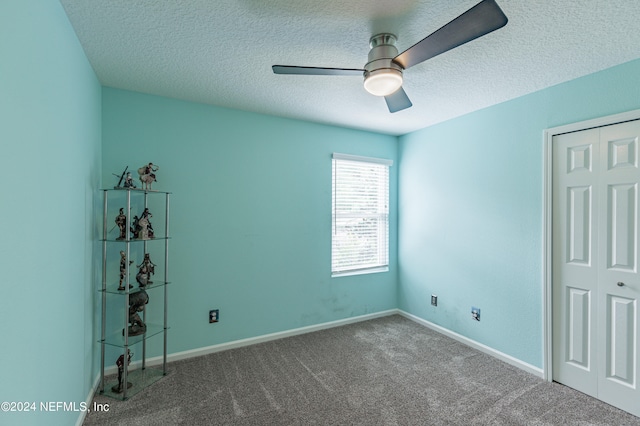 carpeted empty room with ceiling fan and a textured ceiling