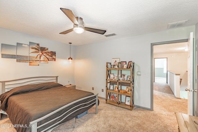 carpeted bedroom featuring ceiling fan and a textured ceiling