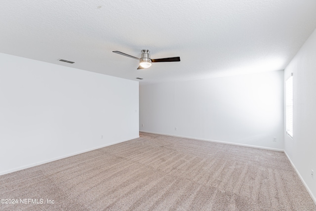 carpeted spare room featuring ceiling fan and a textured ceiling