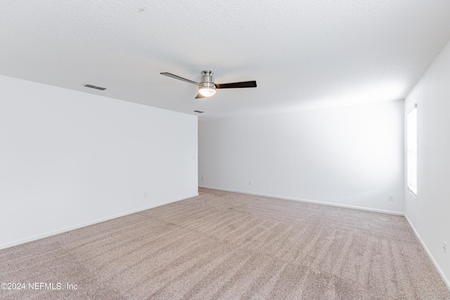 carpeted empty room featuring a textured ceiling, ceiling fan, and baseboards