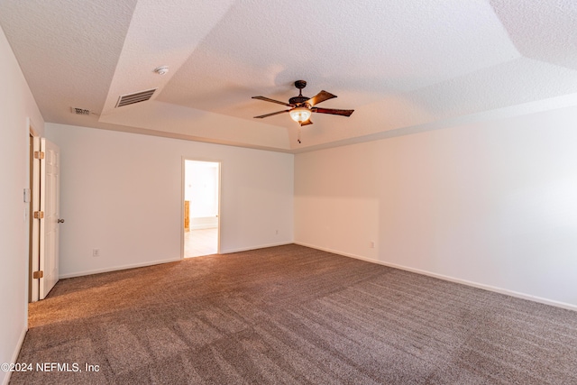 carpeted spare room featuring a tray ceiling, visible vents, ceiling fan, and a textured ceiling