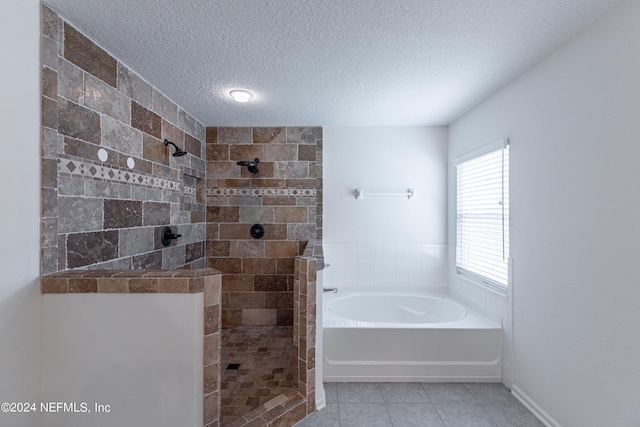 full bathroom featuring a textured ceiling, tile patterned flooring, a tile shower, and a garden tub