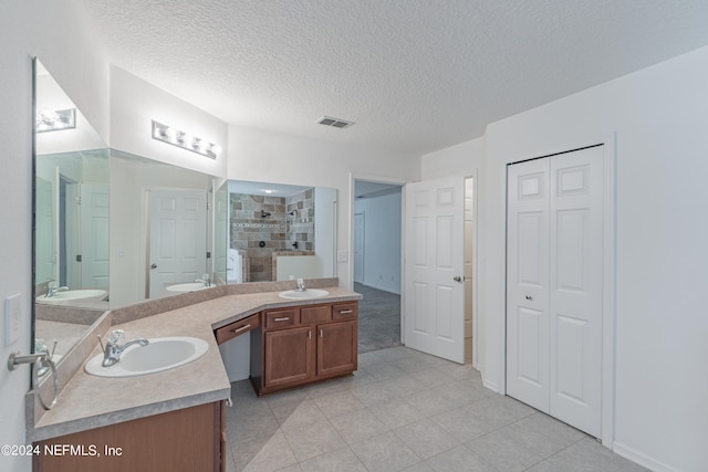 bathroom featuring dual vanity, tile patterned floors, and a textured ceiling