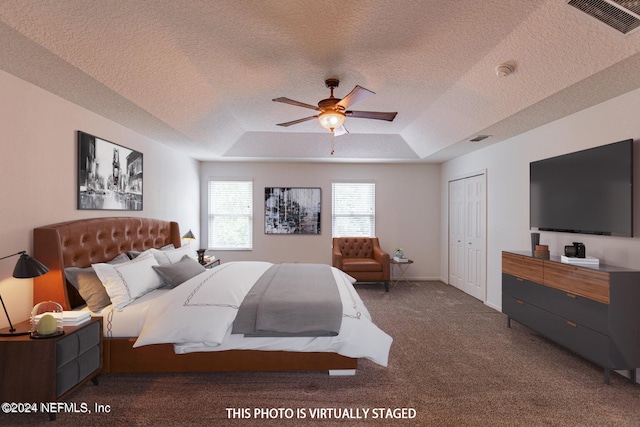 bedroom with dark colored carpet, a closet, ceiling fan, and a raised ceiling