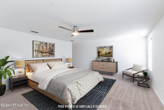 bedroom with ceiling fan, a textured ceiling, and light colored carpet