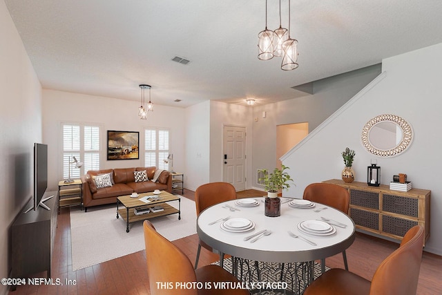 dining area with dark wood-style floors, a chandelier, visible vents, and stairway