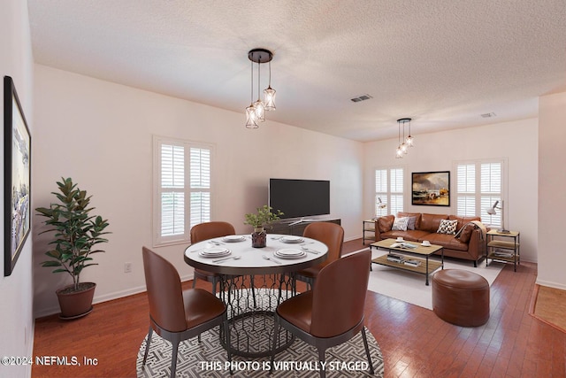 dining room featuring baseboards, a textured ceiling, visible vents, and hardwood / wood-style floors