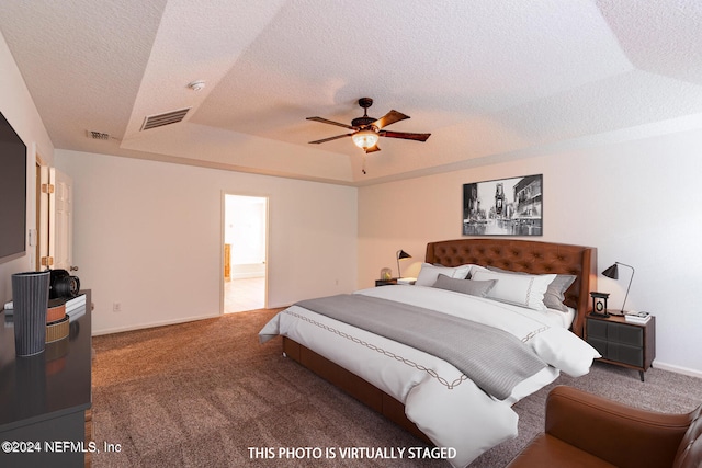 carpeted bedroom with a textured ceiling, a tray ceiling, and ceiling fan