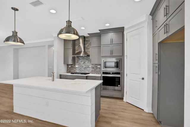 kitchen featuring stainless steel appliances, wall chimney exhaust hood, tasteful backsplash, and hanging light fixtures