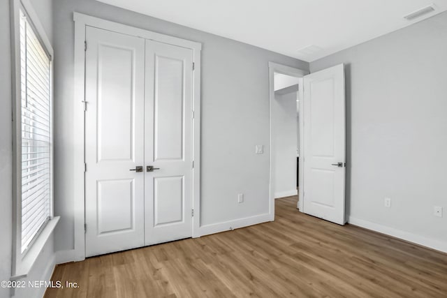 unfurnished bedroom featuring a closet, light hardwood / wood-style floors, and multiple windows