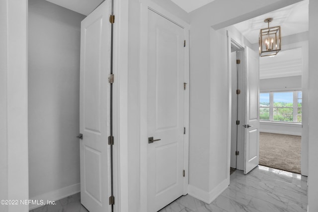 corridor featuring light colored carpet and a chandelier