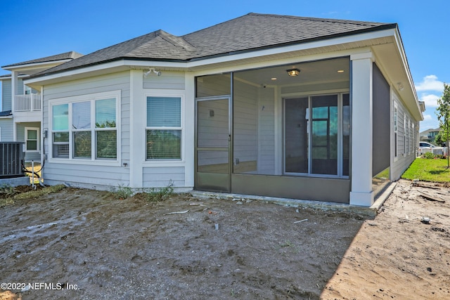 rear view of house with central AC unit and a sunroom