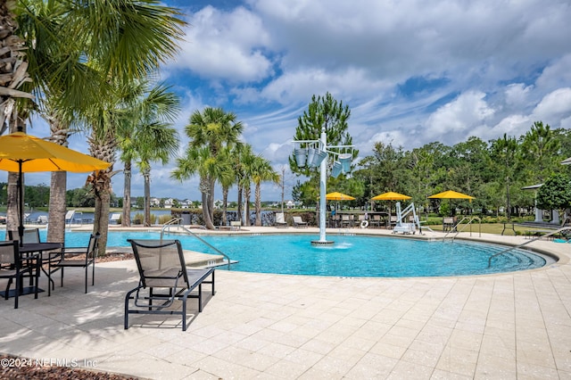 view of swimming pool with pool water feature and a patio