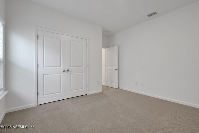 unfurnished bedroom with light carpet and a closet