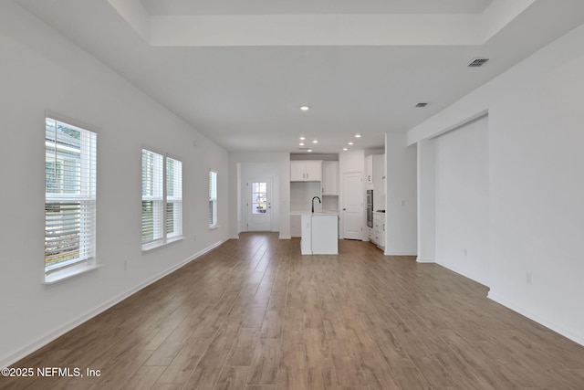 unfurnished living room with sink and light hardwood / wood-style flooring