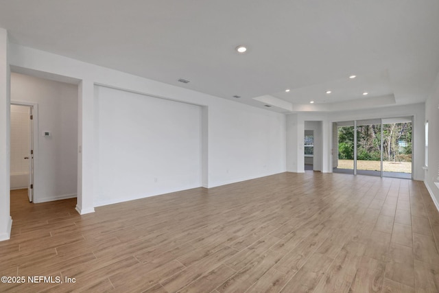 unfurnished living room featuring light hardwood / wood-style floors and a tray ceiling